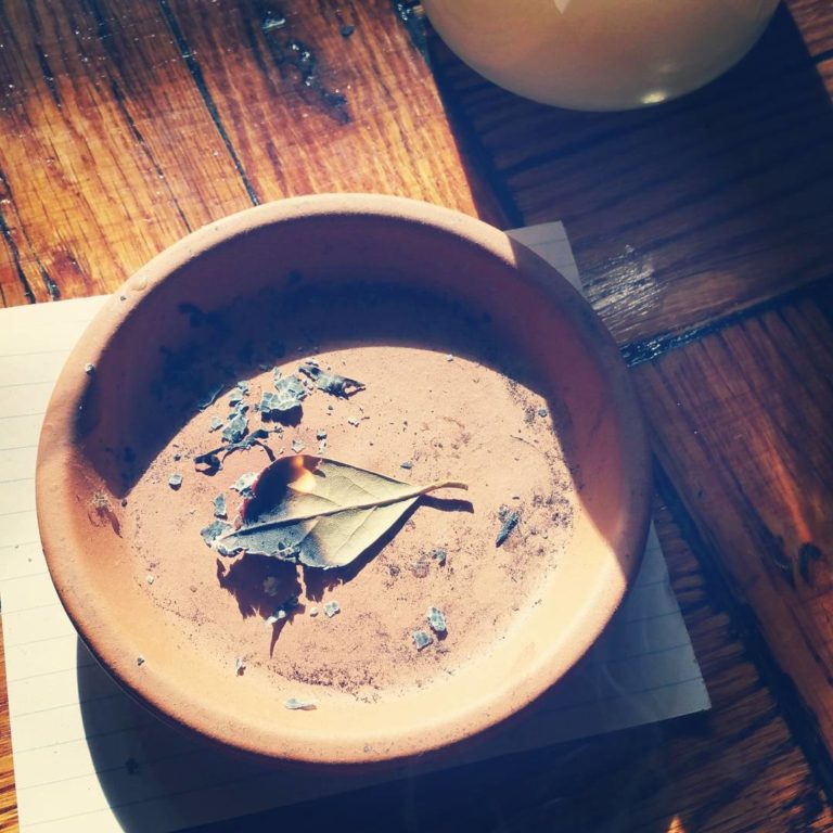 A terracotta dish holding a burning bay leaf. 
