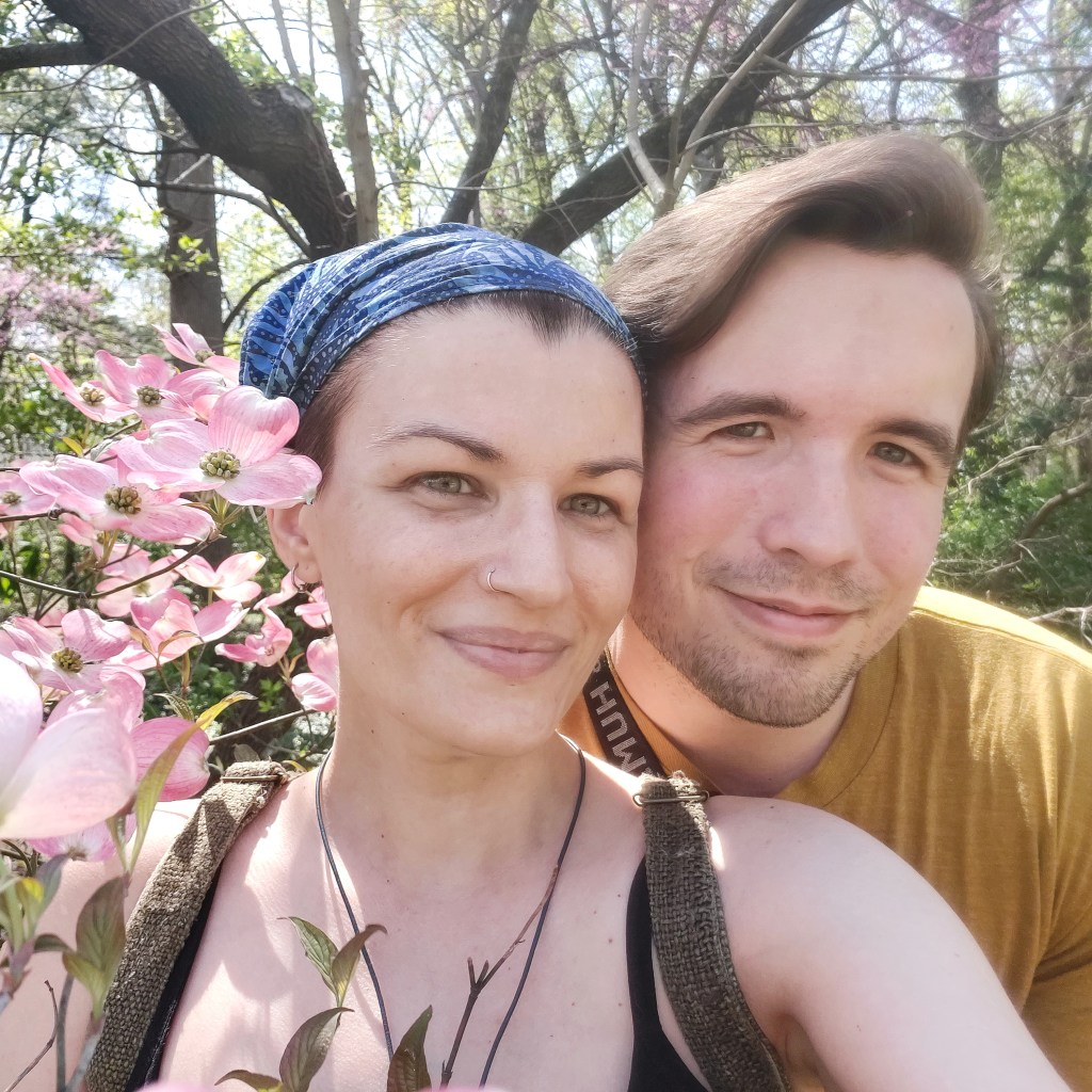 A photo of my partner and me, framed by some dogwood flowers. 
