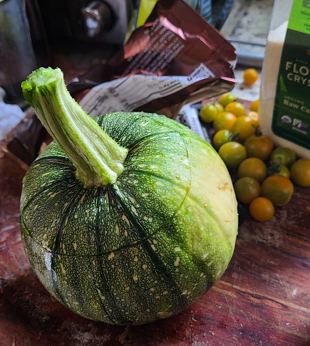 A darker green, speckled, pumpkin-like fruit on a wooden cutting board.