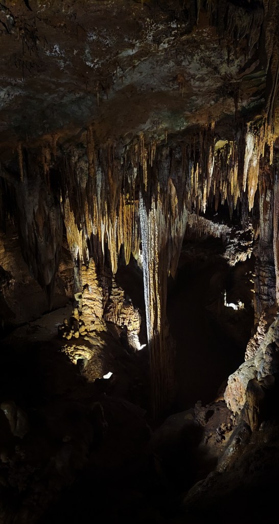 Another formation, primarily of stalactites. One group has grown down to meet the stalagmites on the cave floor, forming a long, continuous pillar. 