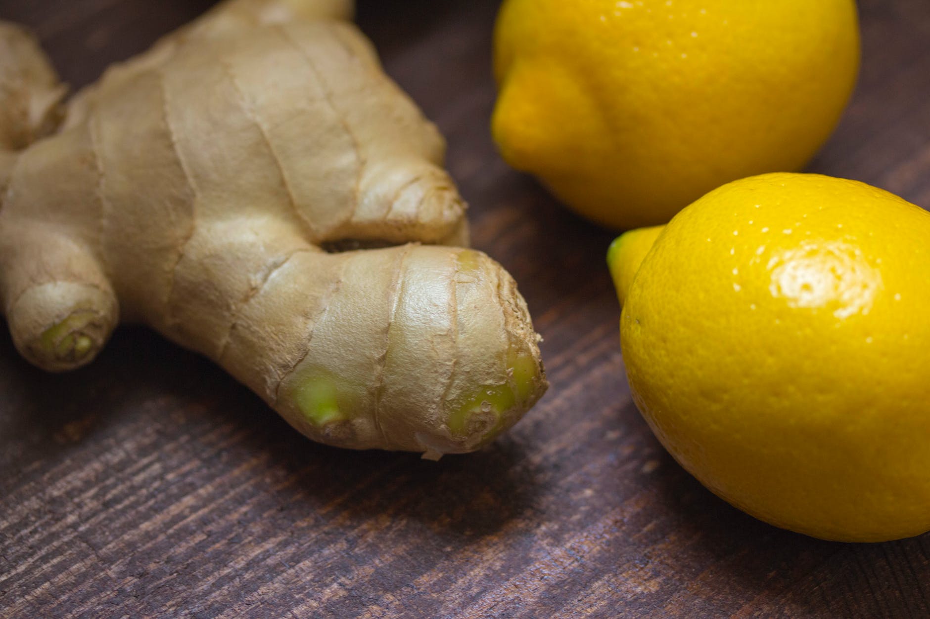 A knobby root of fresh ginger, alongside some whole lemons. 