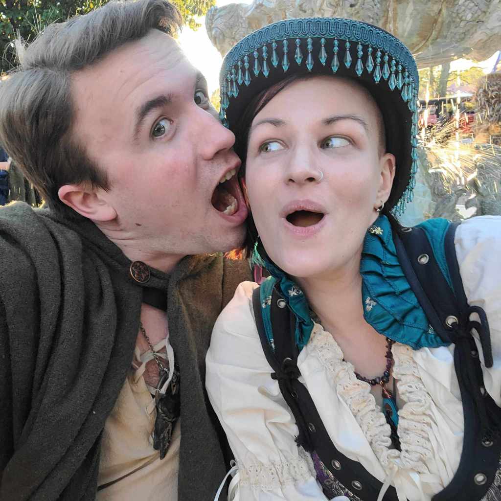 The author and their Handsome Assistant. He's pretending to eat their face, and they're wearing an exaggerated expression of shock. 