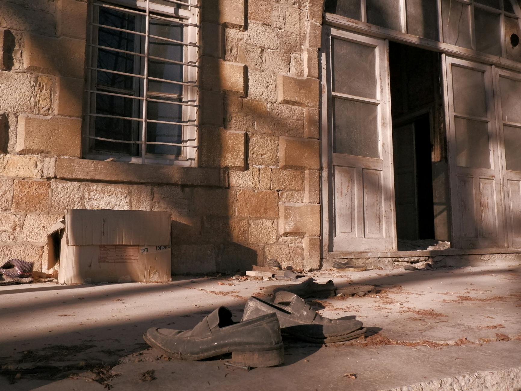 Old shoes left in front of an abandoned building.