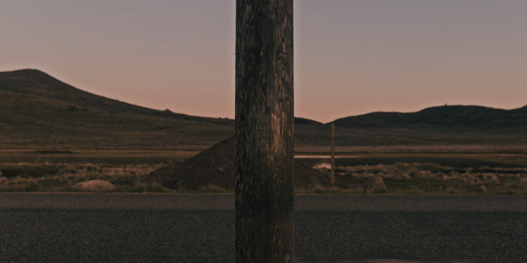 Paimon's insignia carved on a telephone pole on an empty stretch of road. 